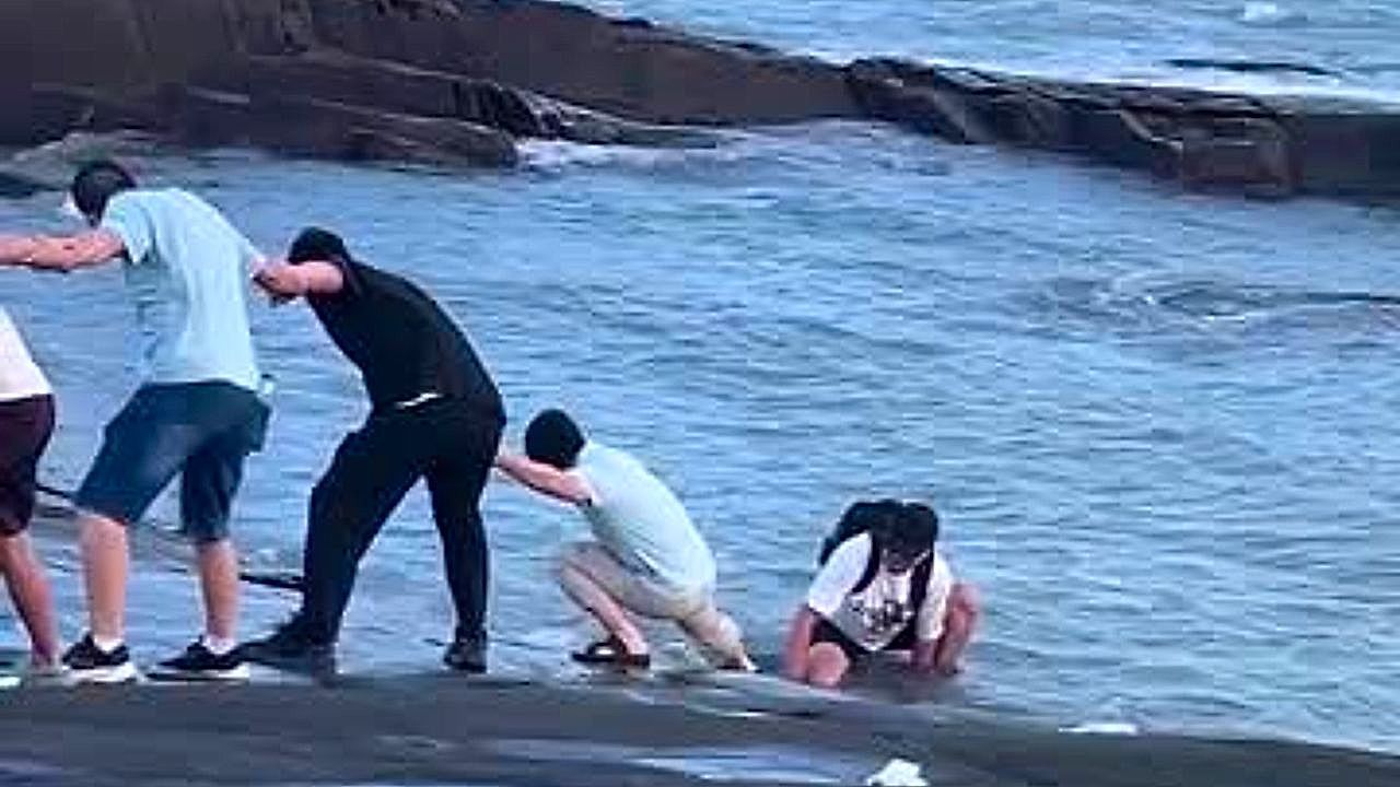 Video: Menschenkette gegen die Brandung: Touristen retten gestrandeten Mann in China